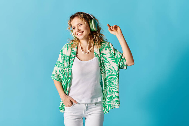 Młoda kobieta ze słuchawkami w zielonej koszuli i białych spodniach. - Zdjęcie, obraz