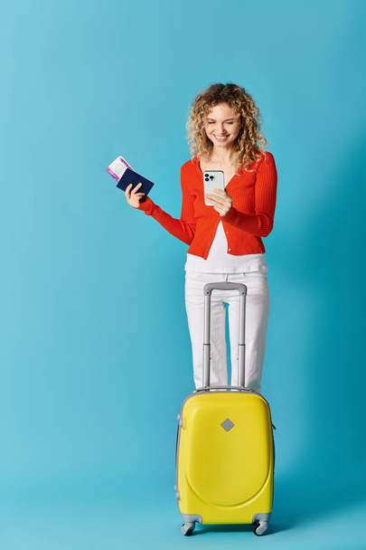 Nő sárga bőrönddel és mobiltelefonnal - Fotó, kép
