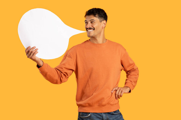 Young man with moustache smiles while holding an empty speech bubble, showing potential for dialogue or messaging - Photo, Image