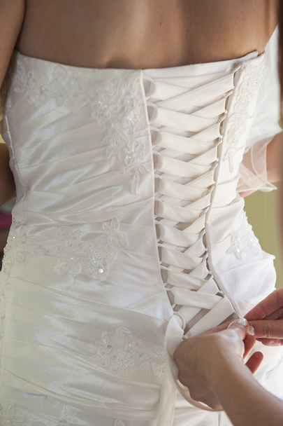 Bride having her dress laced up - Photo, Image