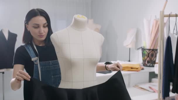 Una mujer está trabajando en un maniquí en una tienda de ropa. Ella sostiene un sujetador negro en su mano - Metraje, vídeo