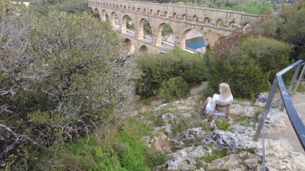 Una viaggiatrice ammira il patrimonio mondiale dell'UNESCO, il Pont du Gard, nel paesaggio sereno della Provenza in Francia. - Filmati, video