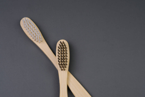 Twee houten tandenborstels worden naast elkaar op een vlak oppervlak geplaatst. De borstels zijn gemaakt van hout met borstels aan de bovenkant. - Foto, afbeelding