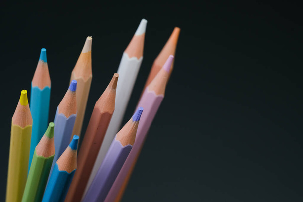 Несколько цветных карандашей разных цветов аккуратно расставлены и хранятся в чашке, ожидая, чтобы их использовали для рисования или раскраски.. - Фото, изображение
