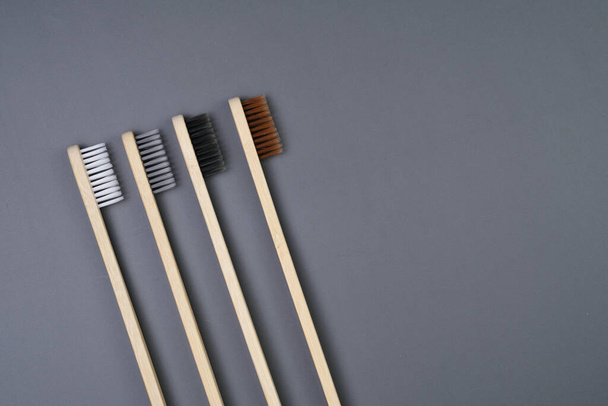 3つの木製の歯ブラシは平らな表面の側面によってきちんと置かれ,自然な材料および簡単な設計を示します. - 写真・画像