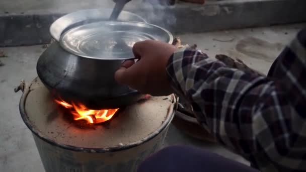 Experimente el auténtico encanto de la cocina al aire libre en Uttarakhand, India, como una olla de arcilla con llamas rojas proporciona calidez y sabor - Metraje, vídeo