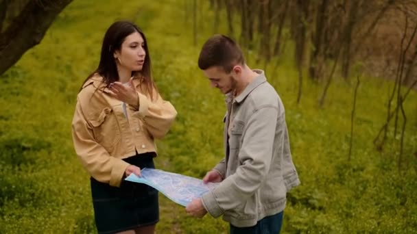 Haritalı genç bir çift, orman gezginleri. Yönlendirme araçlarını, haritaları ve navigasyon uygulamalarını buluyorlar.. - Video, Çekim