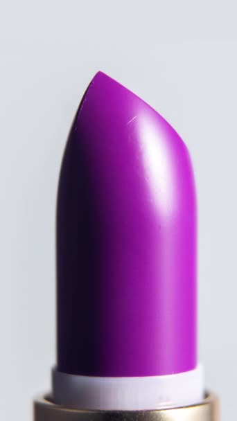 Close-up footage of bright coloured lipstick turning against a plain white background in vertical format - Footage, Video