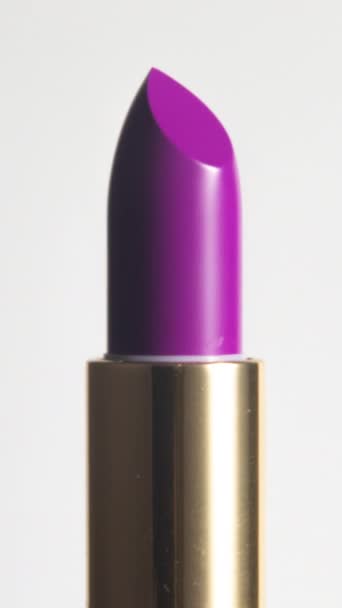 Close-up footage of bright coloured lipstick turning against a plain white background in vertical format - Footage, Video