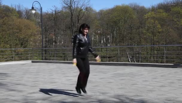 Молодая красивая женщина прыгает через скакалку в городском парке
 - Кадры, видео