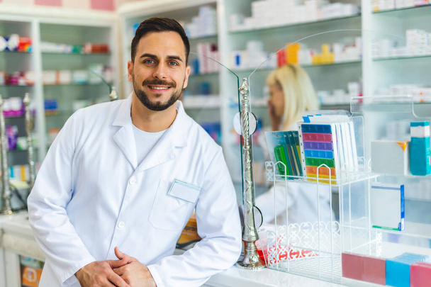 Retrato sonriente de un joven guapo farmacéutico masculino en la farmacia, farmacia. - Foto, imagen