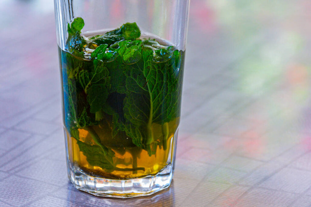 Szklanka mauretańskiej lub zielonej herbaty, z liśćmi mięty, na stole herbaciarni - Zdjęcie, obraz