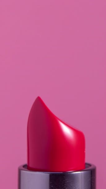 Images en gros plan de rouge à lèvres de couleur vive tournant sur un fond blanc uni en format vertical - Séquence, vidéo