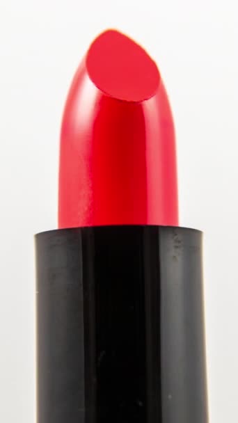 Images en gros plan de rouge à lèvres de couleur vive tournant sur un fond blanc uni en format vertical - Séquence, vidéo