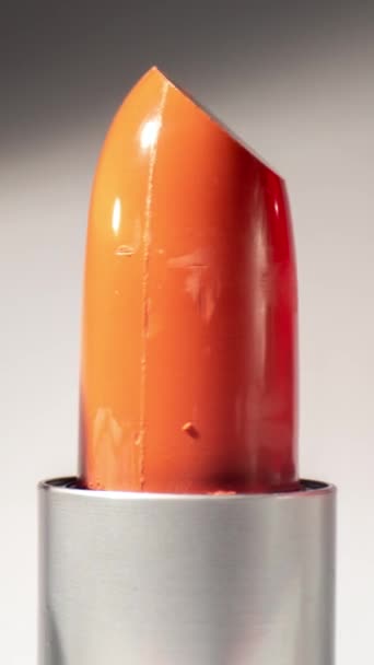 Imágenes de primer plano de lápiz labial de color brillante girando contra un fondo blanco liso en formato vertical - Imágenes, Vídeo