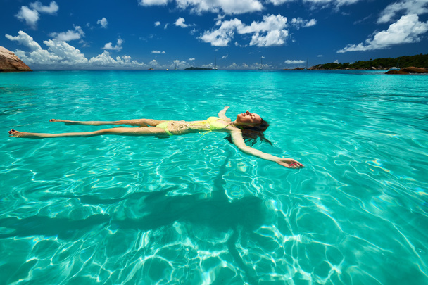 水の上に横たわるビキニの女性 - 写真・画像