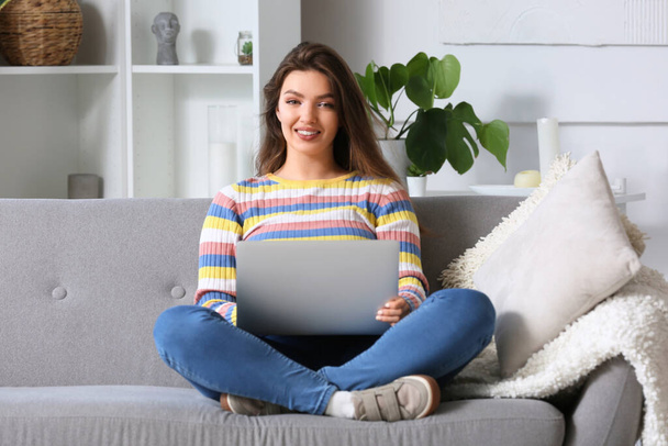 Female freelancer working with laptop on sofa at home - Photo, Image