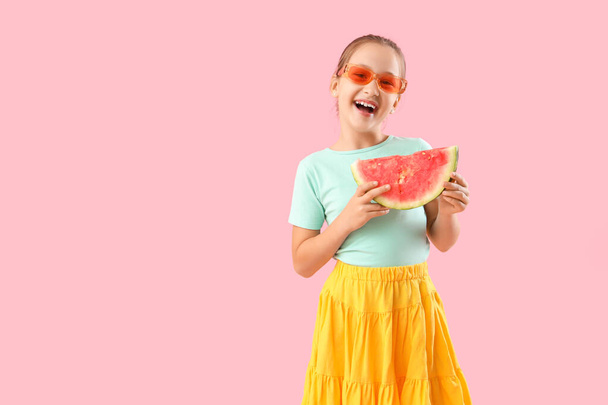 Szczęśliwa dziewczynka w okularach przeciwsłonecznych z plasterkiem świeżego arbuza na różowym tle - Zdjęcie, obraz