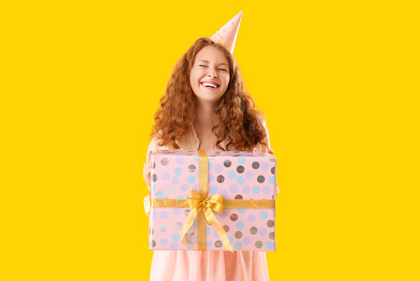 Joyeux beau femme avec cadeau d'anniversaire sur fond jaune - Photo, image