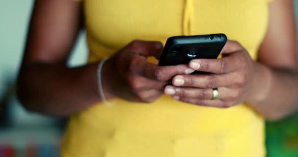 One young black woman using cellphone device standing up. African American 20s person holding phone engaged with modern technology - Footage, Video