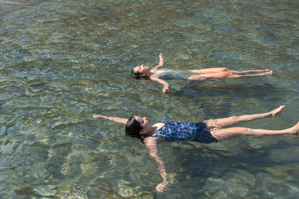 Dwie osoby ćwiczą pływanie, ciesząc się spokojem oceanu. - Zdjęcie, obraz