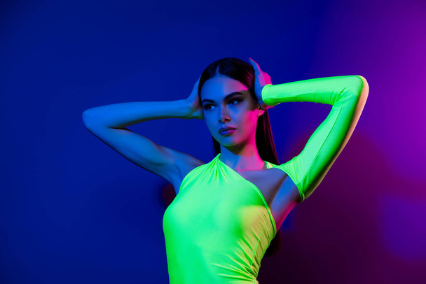 Porträt der schönen Modell Mädchen Hände berühren Haar Kopf suchen leeren Raum ad isoliert auf hellen Neon-Hintergrund. - Foto, Bild