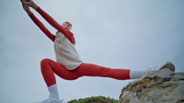 Silna kobieta squatting natura trening zdrowe ciało elastyczność dolny widok. Profesjonalny sportowiec wykonujący codzienny trening na pochmurnym niebie. Miłośnik fitness w czerwonej odzieży sportowej w ćwiczeniach siłowych - Materiał filmowy, wideo