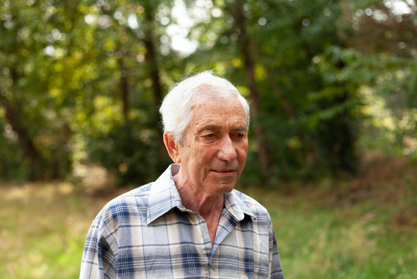 Essentie van een oudere man in een geruit hemd genietend van de rust en schoonheid van de natuur - Foto, afbeelding