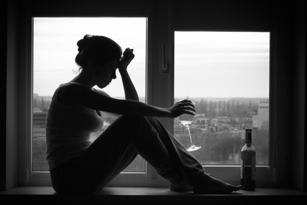 Woman in depressed mood sits on the window - Foto, Imagen