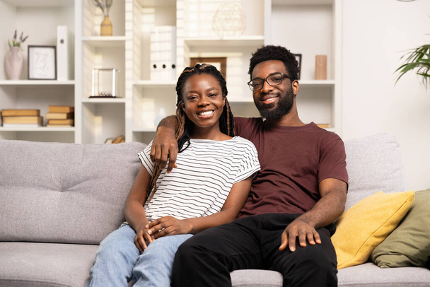 Happy Couple At Home, Young Adults Sitting On Couch, Living Room Interior, Cheerful Togetherness, Casual Style, Smiling At Camera - Foto, Imagem