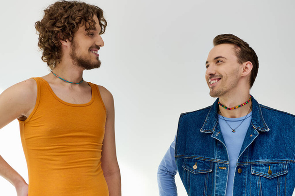 appealing happy lgbt friends in vivid attires looking at each other on gray backdrop, pride month - Photo, Image