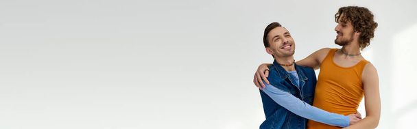 boa aparência alegre lgbtq amigos em roupas vibrantes abraçando no fundo cinza, mês de orgulho, banner - Foto, Imagem
