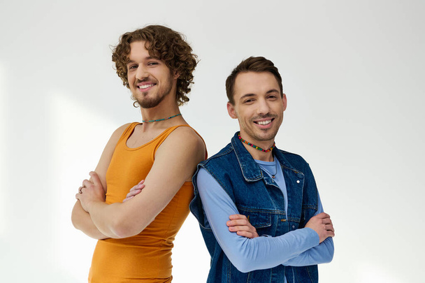 alluring cheerful lgbtq friends in stylish outfits posing on gray backdrop and looking at camera - Φωτογραφία, εικόνα