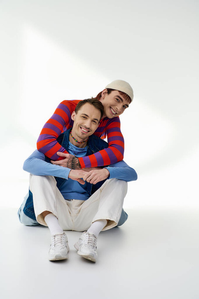 two merry good looking lgbt friends in vibrant attires looking at camera posing on gray backdrop - Photo, Image