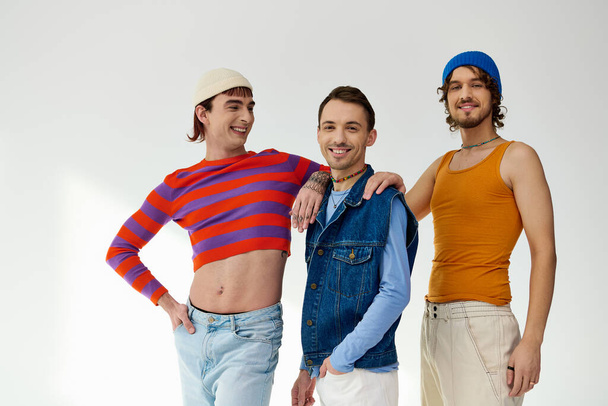 joyous good looking lgbtq male friends in casual vibrant outfits posing actively on gray backdrop - Photo, Image