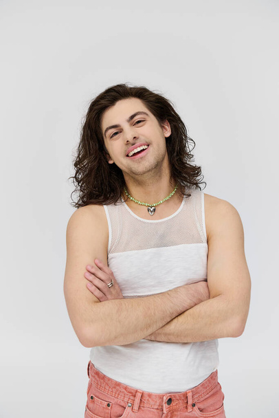cheerful appealing gay man with long hair in casual attire smiling at camera on gray backdrop - Φωτογραφία, εικόνα