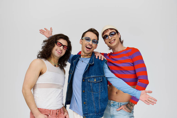 trzy voguish atrakcyjne przyjaciele gej w tętniące życiem modne stroje w eleganckie okulary przeciwsłoneczne, duma miesiąc - Zdjęcie, obraz
