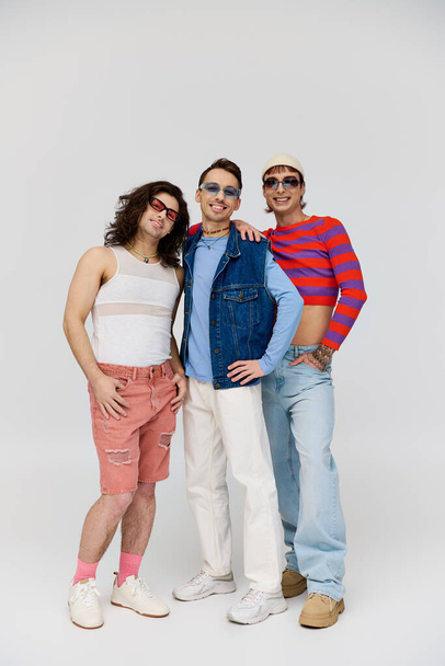 three modish appealing gay friends in vibrant trendy attires with chic sunglasses, pride month - Foto, Bild