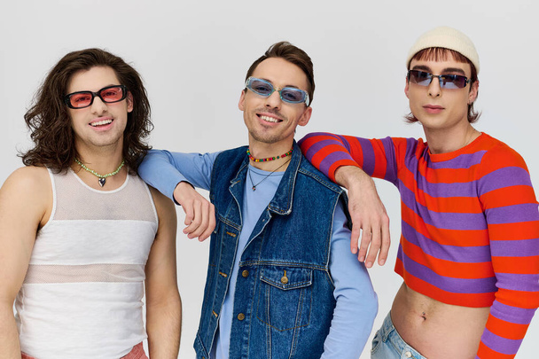 tres amigos gay atractivos de moda en vibrantes trajes de moda con gafas de sol elegantes, mes de orgullo - Foto, Imagen