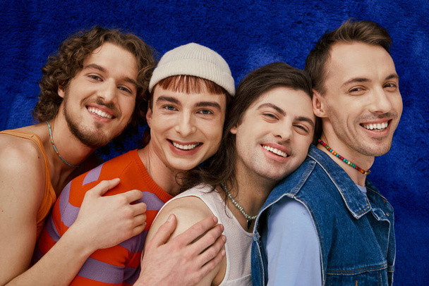 cztery radosne atrakcyjne stylowe geje przyjaciele w codzienne jasne ubrania na niebieskim tle, duma miesiąc - Zdjęcie, obraz