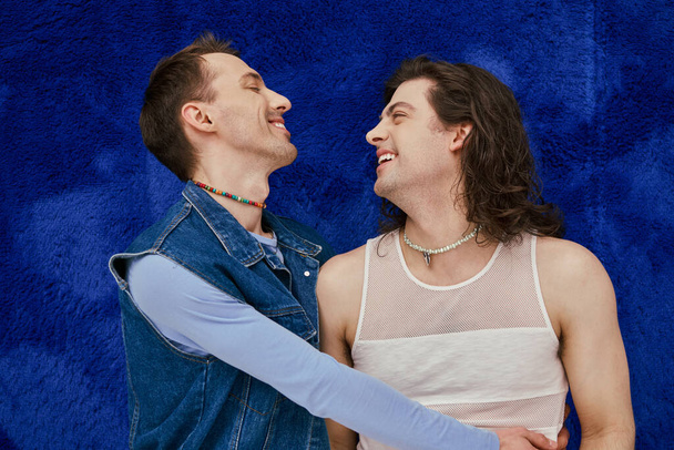 Tyytyväinen houkutteleva tyylikäs homo ystäviä viihtyisä asuja tummansininen tausta, ylpeys kuukausi - Valokuva, kuva