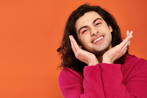 joyful good looking gay man with long hair in magenta sweatshirt looking at camera, pride month - Photo, Image