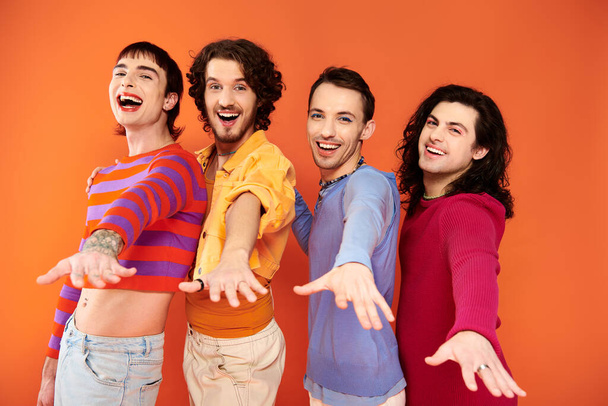 cheerful young gay men with makeup in vibrant attires posing actively together, pride month - Foto, Bild