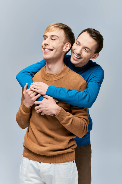 カジュアルな服装の2人の男が笑顔で抱き合う. - 写真・画像