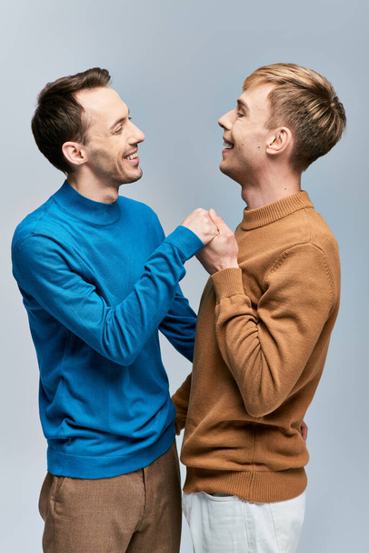 Dva muži v neformálním oděvu stojí bok po boku a drží se za ruce. - Fotografie, Obrázek