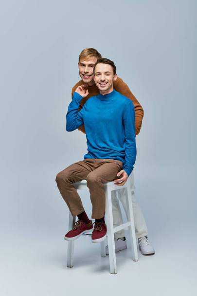 Zwei Männer in Freizeitkleidung posieren vor grauem Hintergrund. - Foto, Bild