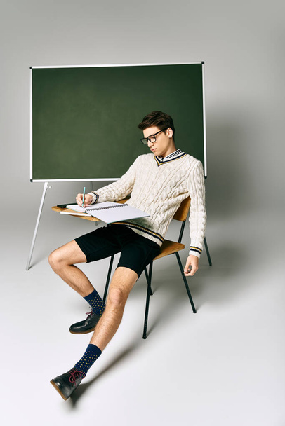 Mężczyzna na krześle przy tablicy na studiach.. - Zdjęcie, obraz