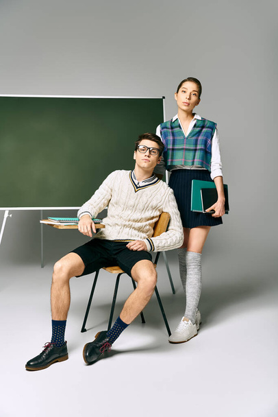 Un hombre y una mujer con estilo de pie frente a un tablero verde en la universidad. - Foto, Imagen