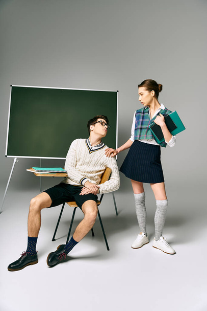 Elegantní muž a žena sedí před zelenou desku na vysoké škole. - Fotografie, Obrázek