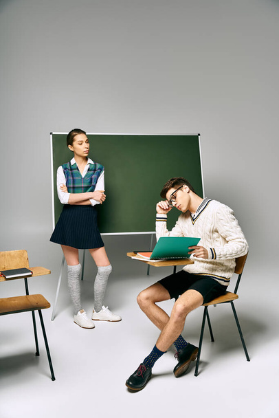 Άνδρες και γυναίκες μαθητές κάθονται κομψά μπροστά από ένα πράσινο πίνακα σε ένα περιβάλλον κολλεγίου. - Φωτογραφία, εικόνα